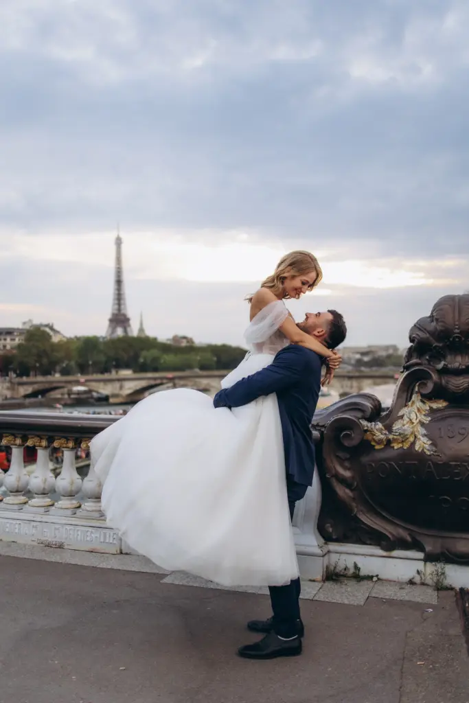 Groom lifting the bride on Pont Alexandre III, Eiffel Tower on the horizon