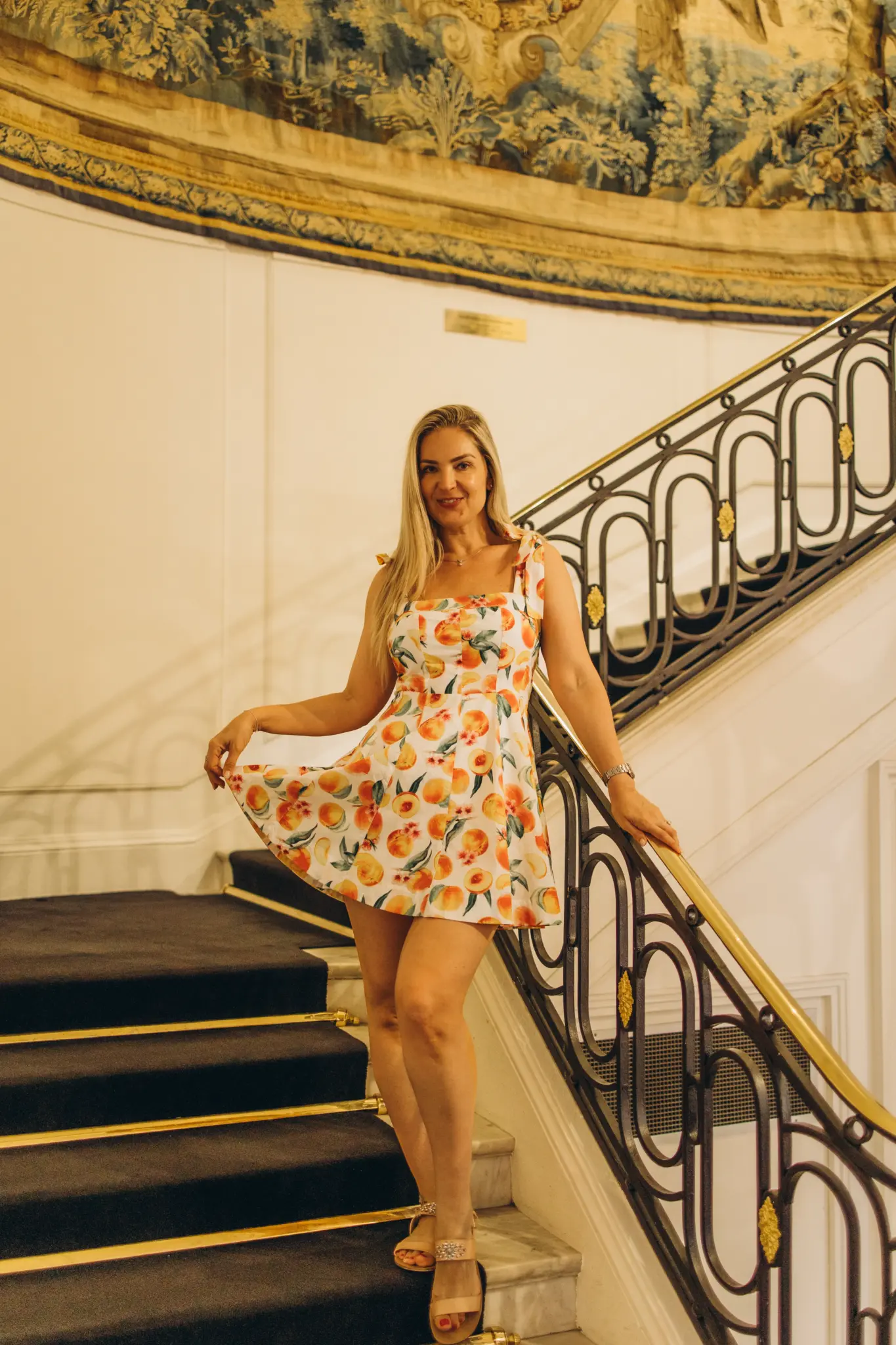 Woman in a floral dress on an ornate staircase in a grand hotel in Nice